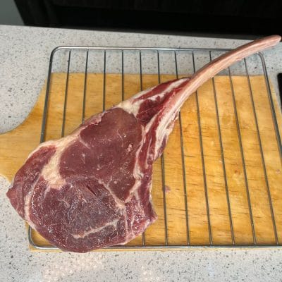 Un corte tomahawk sobre una rejilla metálica y una tabla de madera